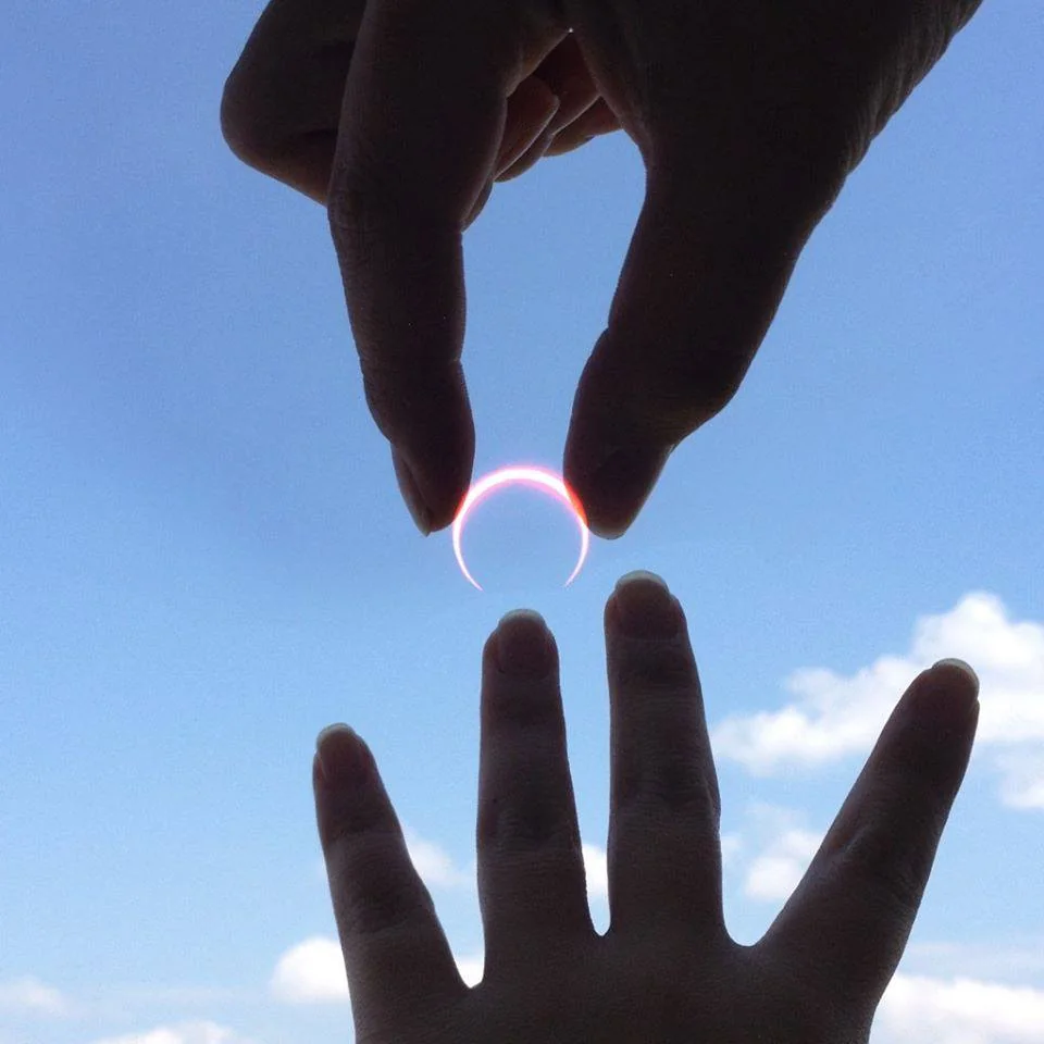 Two hands reaching toward each other against a blue sky