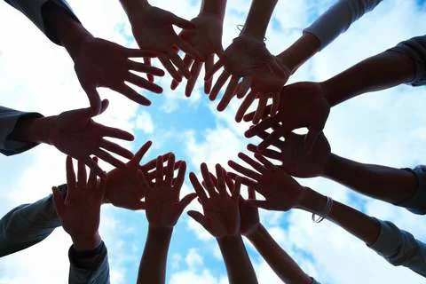 Hands reaching inward to form a circle against the sky