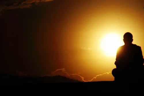 Silhouette of a seated person meditating at sunset