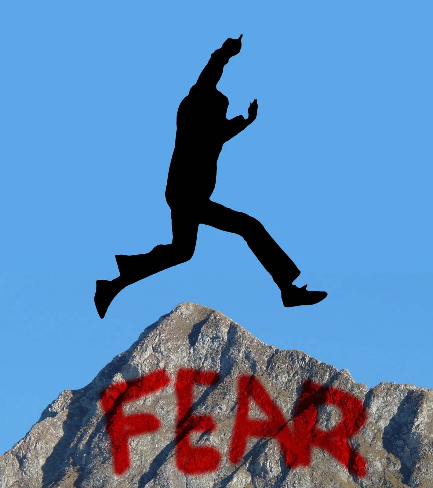 Silhouette jumping over rocks bearing the word fear