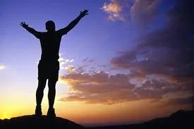 Person with arms raised against a sunset sky