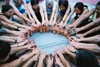 Women extending their hands into the centre of a circle